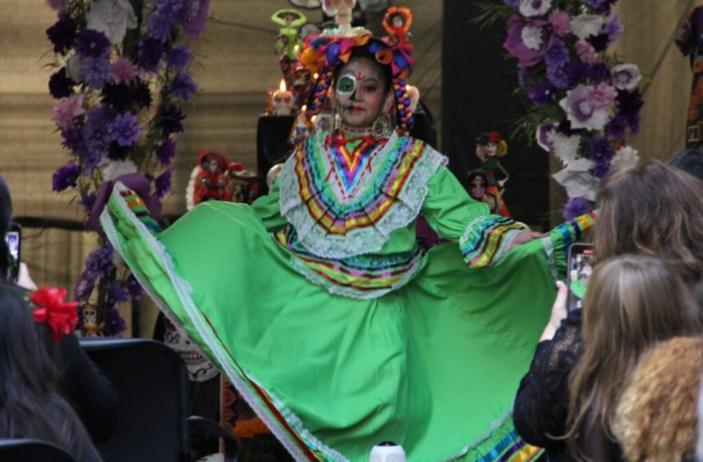 A folklorico dancer in vibrant green traditional dress performs at a community cultural event in Marin County supporting Center for Domestic Peace’s mission to end domestic violence.