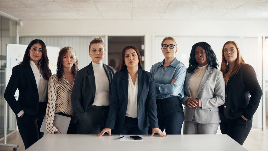 Diverse group of confident and successful businesswomen standing side by side with their manager in the boardroom of an office.