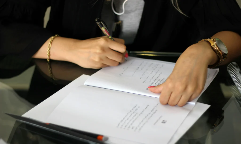 A person writes in a legal document on a table, symbolizing planned giving through wills or trusts to support survivors of domestic violence in Marin County.
